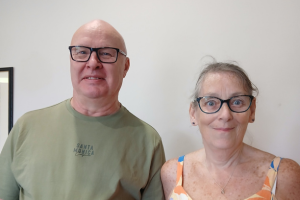 Man (left) and woman (right) standing and smiling for a picture. Chest upwards.